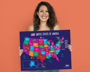 A smiling woman with dark curly hair holds up a large, colorful United States map poster against a solid orange background. The map features each state in a different bright color, with a dark blue border and white text.
